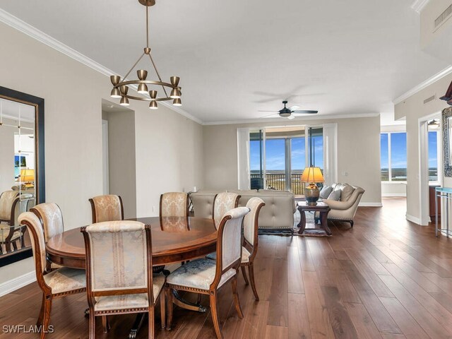 dining room featuring a healthy amount of sunlight, dark wood-type flooring, ceiling fan with notable chandelier, and ornamental molding