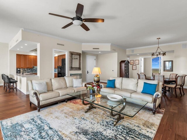 living room featuring dark hardwood / wood-style flooring, ceiling fan with notable chandelier, and ornamental molding