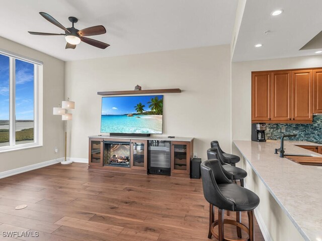 living room with ceiling fan, hardwood / wood-style floors, beverage cooler, and sink