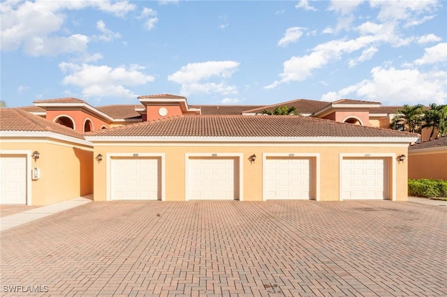 view of front facade featuring community garages, stucco siding, and a tile roof