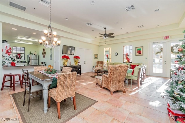 dining area featuring a raised ceiling, french doors, and ceiling fan with notable chandelier