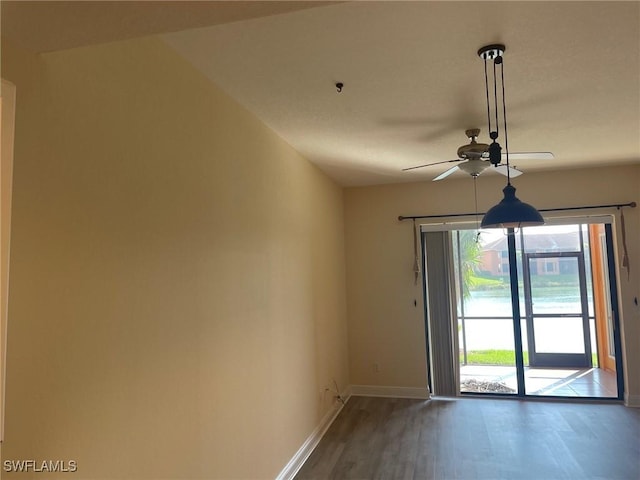 empty room featuring ceiling fan, baseboards, and wood finished floors