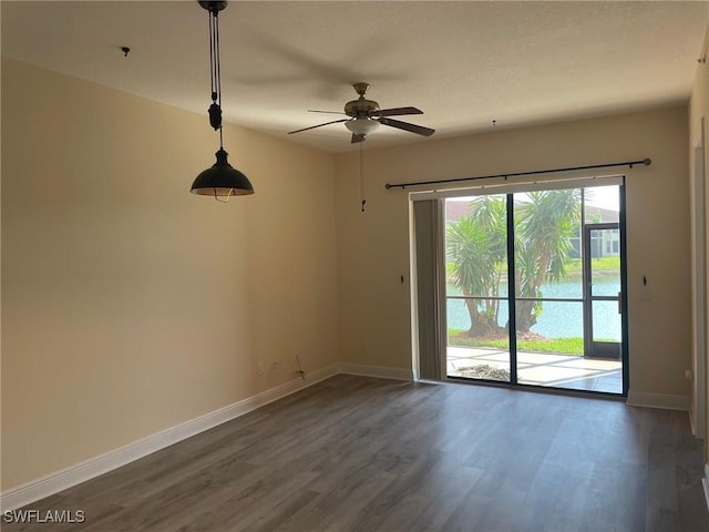 spare room featuring dark wood-type flooring, a ceiling fan, and baseboards