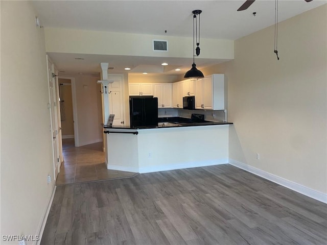 kitchen featuring dark countertops, hanging light fixtures, black appliances, wood finished floors, and baseboards