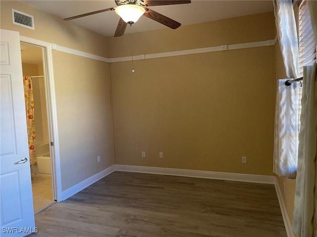 empty room with baseboards, visible vents, ceiling fan, and wood finished floors