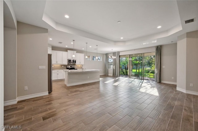 unfurnished living room featuring hardwood / wood-style floors, a chandelier, and a tray ceiling