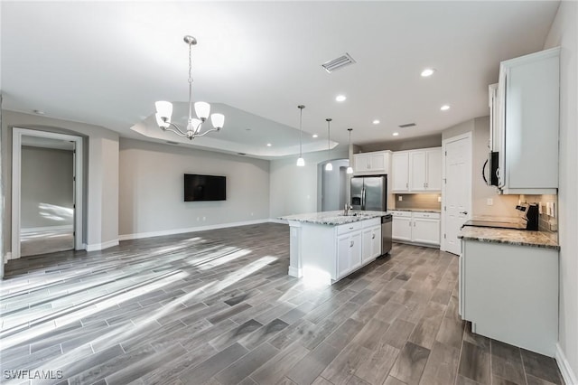 kitchen with stainless steel appliances, wood-type flooring, a center island with sink, white cabinets, and hanging light fixtures