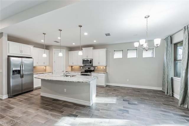 kitchen featuring stainless steel appliances, white cabinetry, hanging light fixtures, and a notable chandelier