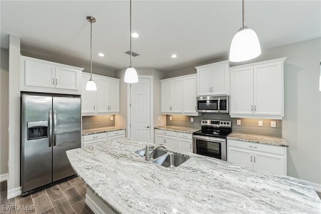 kitchen featuring backsplash, white cabinets, sink, hanging light fixtures, and stainless steel appliances