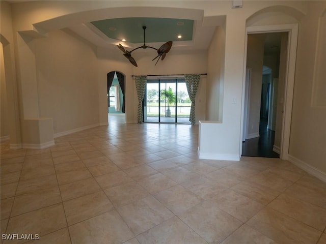 unfurnished room featuring ceiling fan, a raised ceiling, and light tile patterned floors