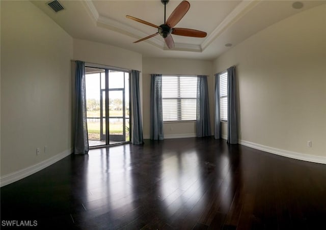 spare room featuring dark hardwood / wood-style floors, ceiling fan, and a tray ceiling