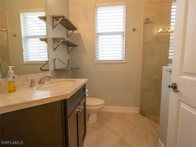 bathroom featuring tile patterned floors, vanity, a tile shower, and toilet