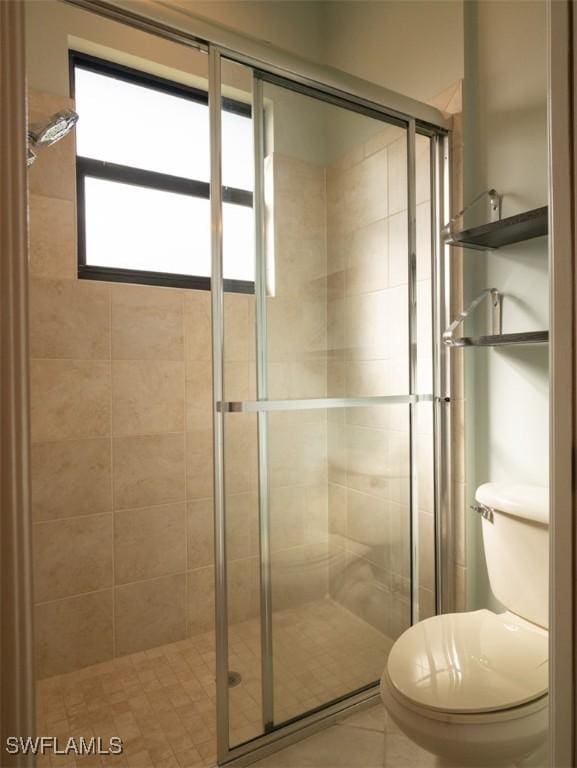 bathroom featuring tile patterned floors, a shower with door, and toilet