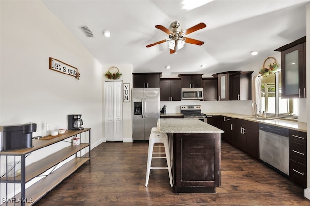 kitchen with vaulted ceiling, a kitchen island, sink, stainless steel appliances, and dark brown cabinets