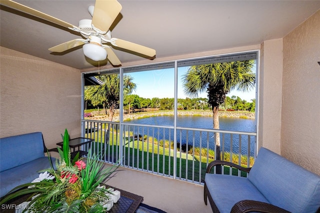 sunroom featuring ceiling fan and a water view