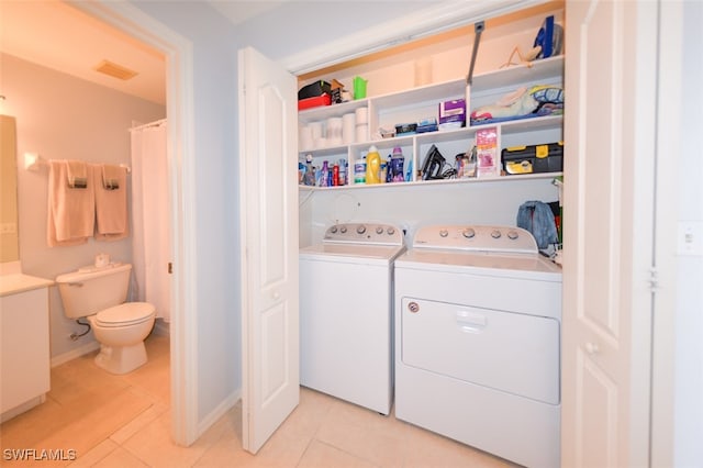 laundry area with washer and clothes dryer and light tile patterned flooring