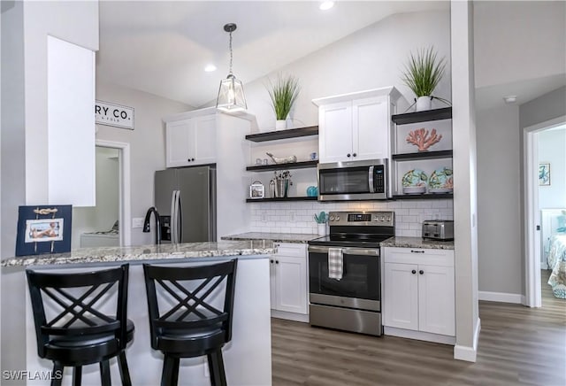 kitchen featuring light stone countertops, stainless steel appliances, white cabinetry, and lofted ceiling