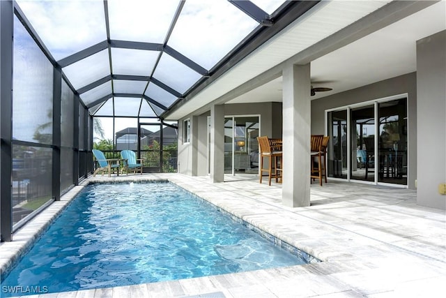 view of swimming pool featuring a patio, glass enclosure, and an outdoor bar