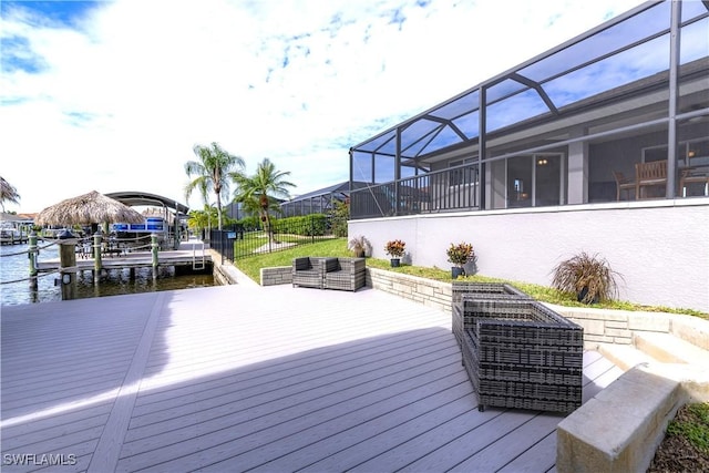 deck with glass enclosure, a water view, and a dock