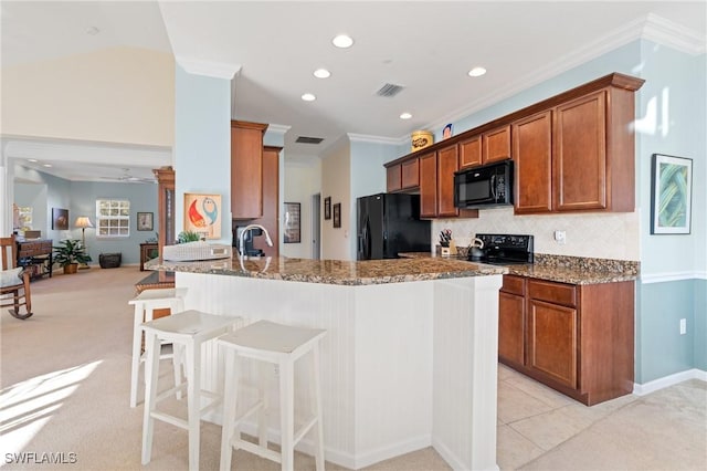 kitchen with black appliances, ceiling fan, stone countertops, light colored carpet, and kitchen peninsula