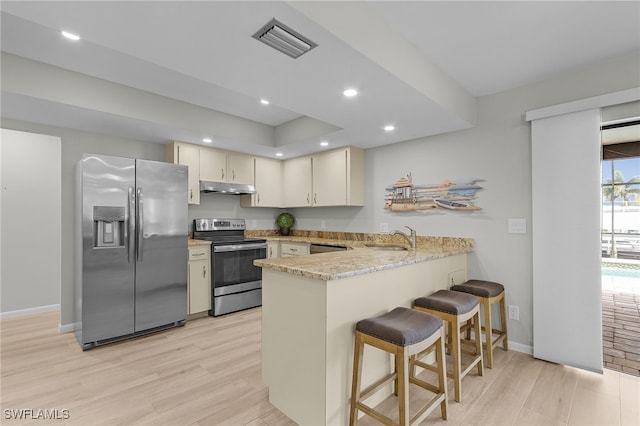 kitchen with kitchen peninsula, light wood-type flooring, stainless steel appliances, sink, and cream cabinetry