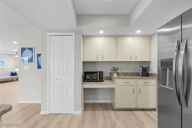 kitchen with stone counters, ceiling fan, light hardwood / wood-style flooring, stainless steel fridge, and cream cabinetry