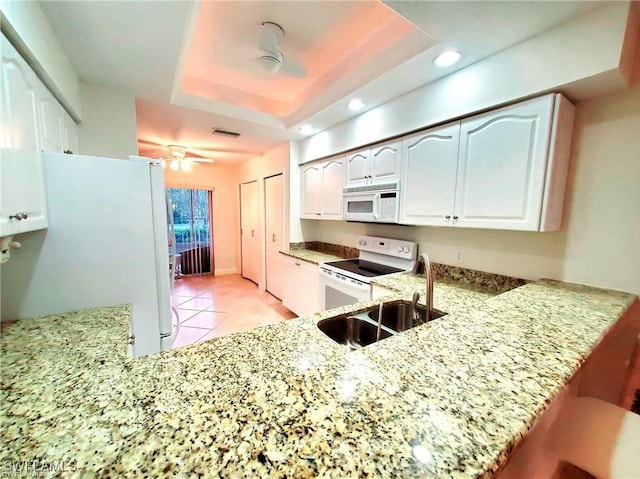 kitchen featuring kitchen peninsula, white appliances, white cabinets, and a tray ceiling