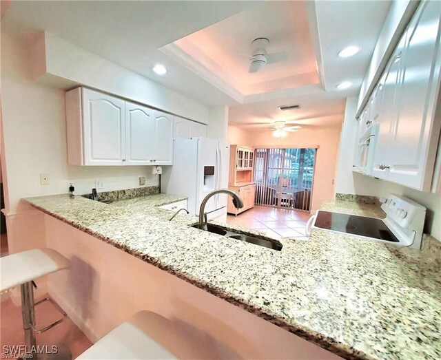 kitchen with white cabinets, sink, white appliances, and kitchen peninsula