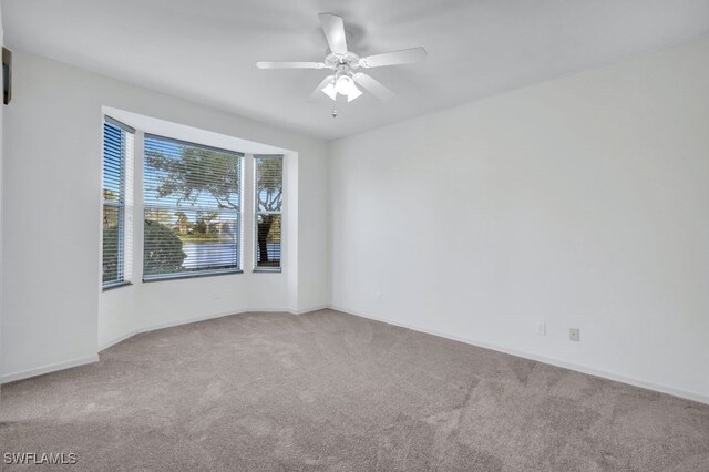 carpeted spare room featuring ceiling fan