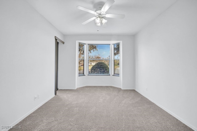 spare room with ceiling fan and light colored carpet