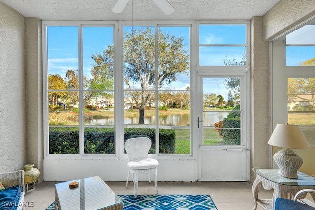 sunroom / solarium featuring ceiling fan and a water view