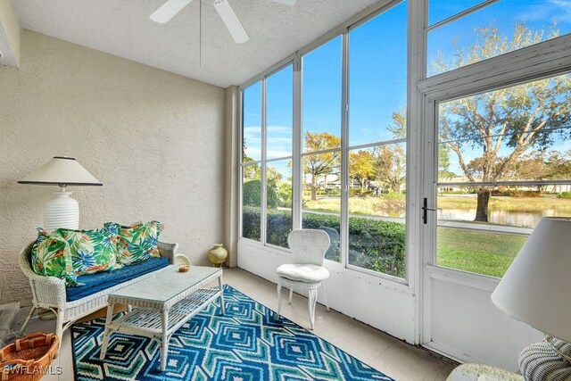 sunroom featuring ceiling fan and a water view