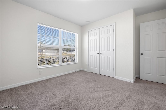 unfurnished bedroom with a closet and light colored carpet