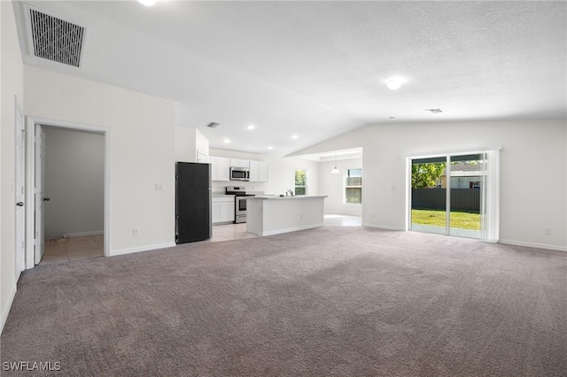 unfurnished living room with light carpet and vaulted ceiling