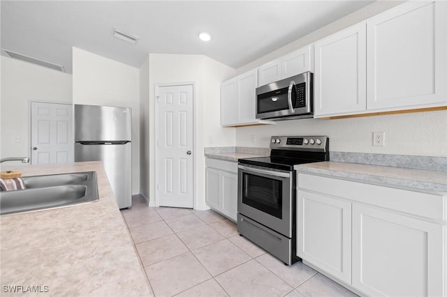 kitchen with light tile patterned flooring, sink, white cabinetry, and stainless steel appliances