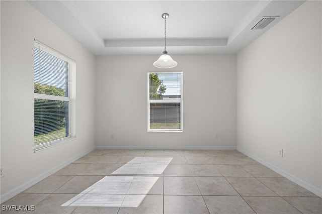 tiled spare room with a raised ceiling and a wealth of natural light