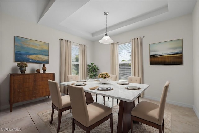 tiled dining space with a raised ceiling