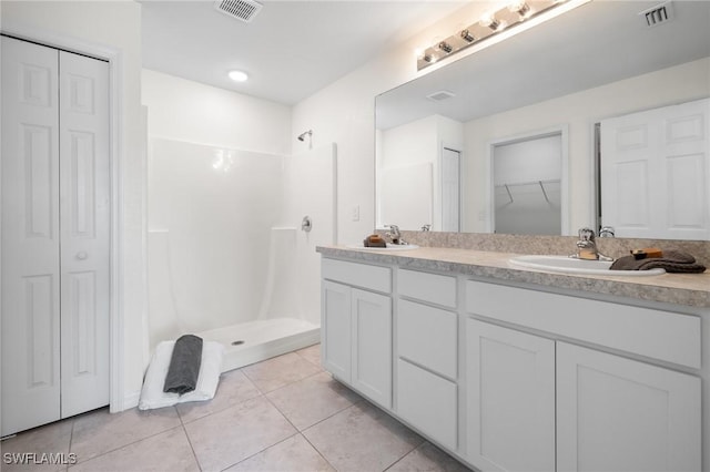 bathroom with tile patterned flooring, vanity, and a shower