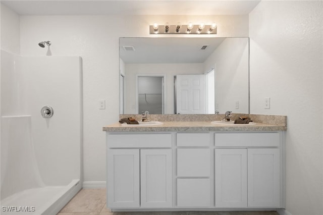 bathroom featuring tile patterned flooring, vanity, and walk in shower