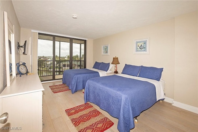 bedroom featuring access to outside, floor to ceiling windows, and light hardwood / wood-style flooring