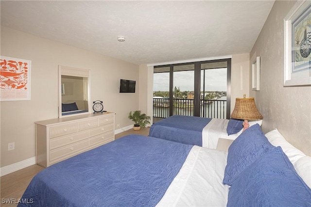 bedroom featuring access to exterior, a textured ceiling, and hardwood / wood-style flooring