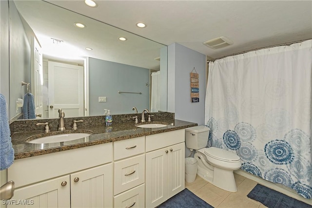 bathroom with toilet, vanity, and tile patterned floors