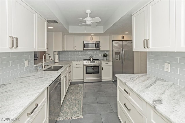 kitchen featuring white cabinets, appliances with stainless steel finishes, backsplash, and sink