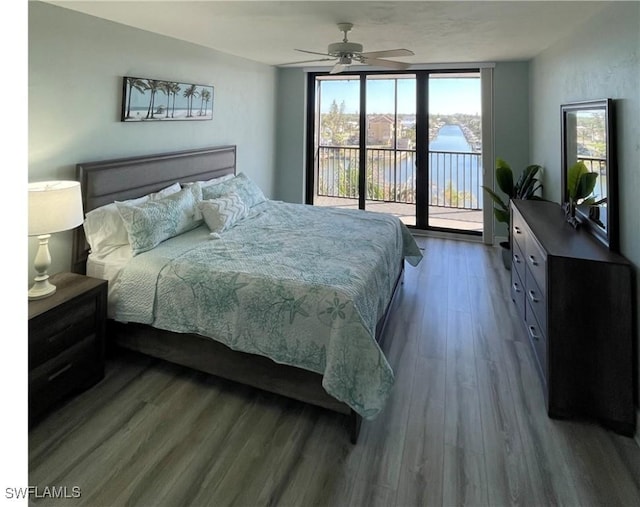 bedroom with hardwood / wood-style floors, ceiling fan, a water view, and access to exterior