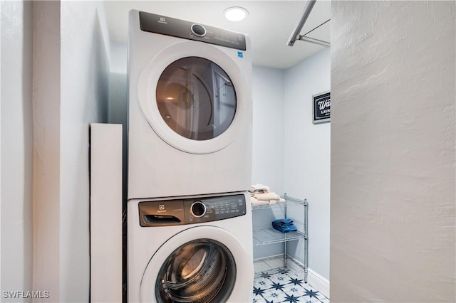 washroom with laundry area, baseboards, and stacked washer / dryer