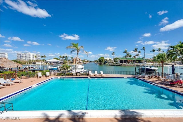 pool with a water view, fence, and a patio