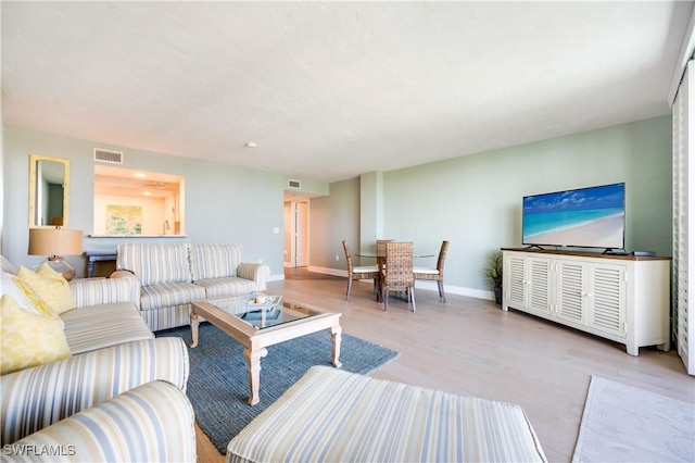 living area with light wood-style flooring, visible vents, and baseboards