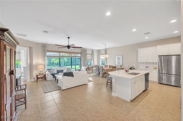 kitchen with ceiling fan, sink, stainless steel appliances, a center island with sink, and white cabinets