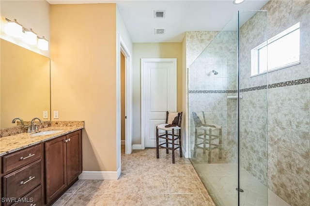 bathroom with a tile shower, vanity, and tile patterned floors