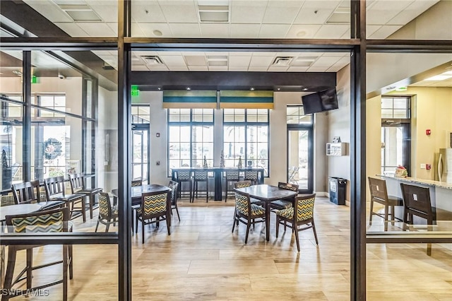 dining room featuring french doors, light hardwood / wood-style floors, and a drop ceiling